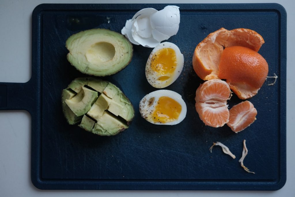 Avocat, oeufs et agrumes sur une planche en bois clair