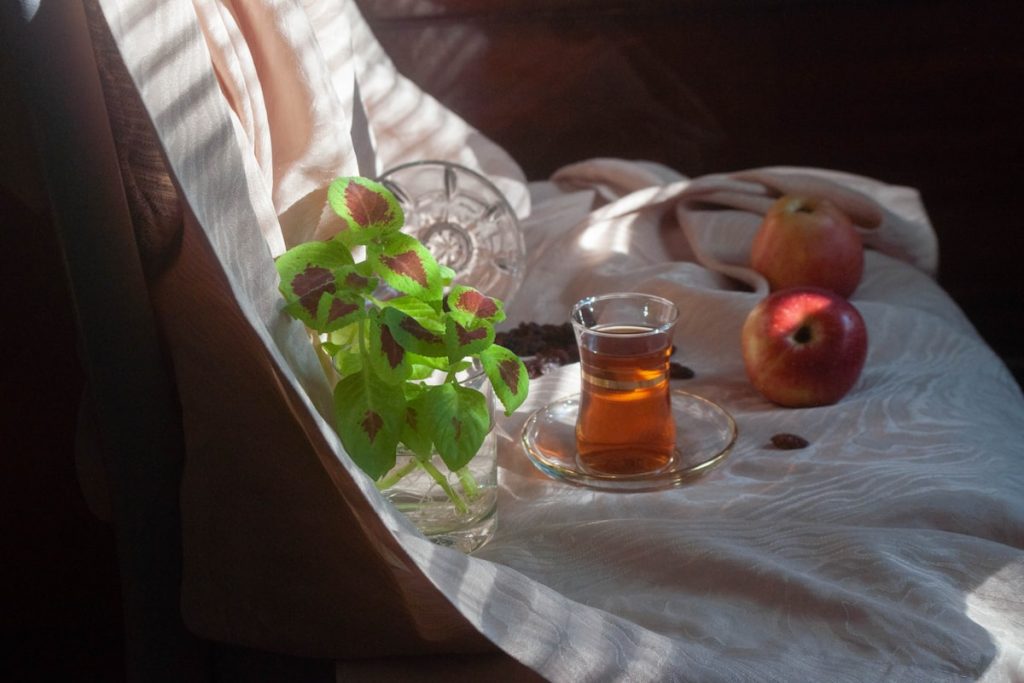 Verre de the vert et pommes sur une nappe en lin clair