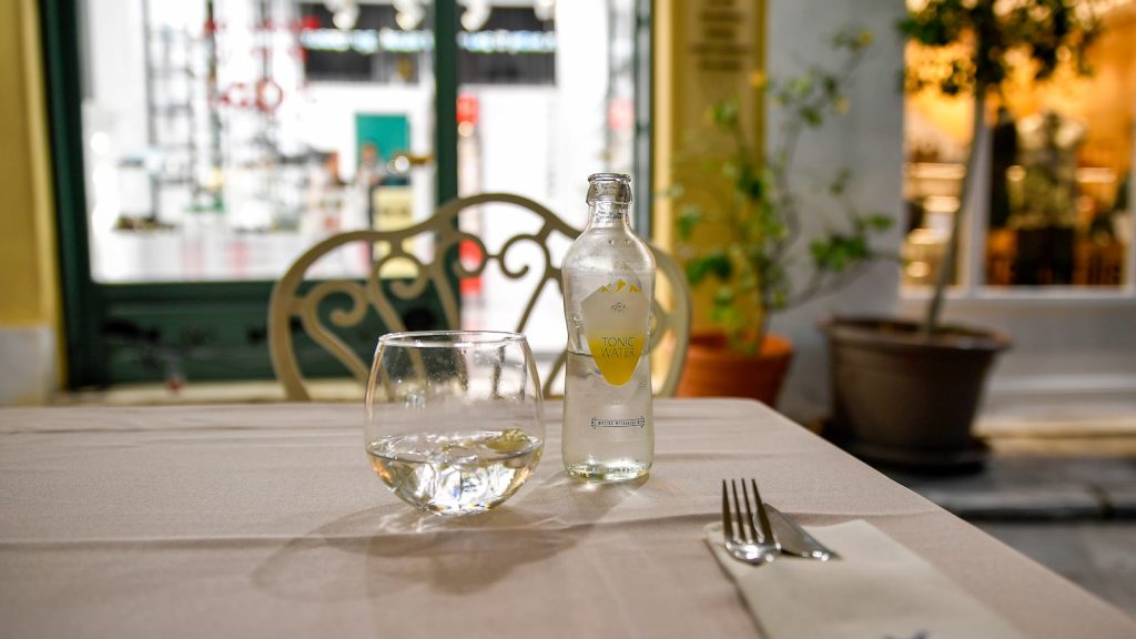 Verre de vin rouge posé près d'une assiette, lumière tamisée de fin de repas