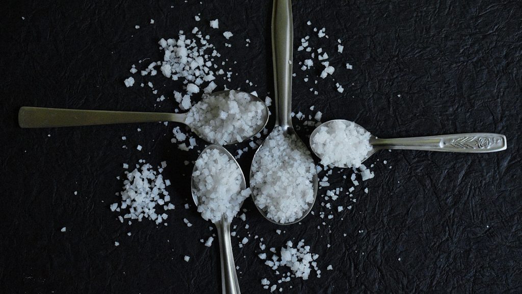Cuillère de sucre blanc en poudre posée sur un plan de travail de cuisine clair