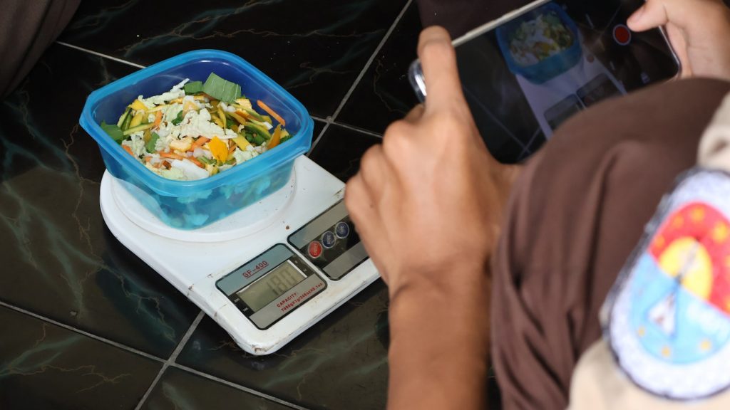 Personne pesant un aliment et saisissant les valeurs sur une application de suivi nutritionnel