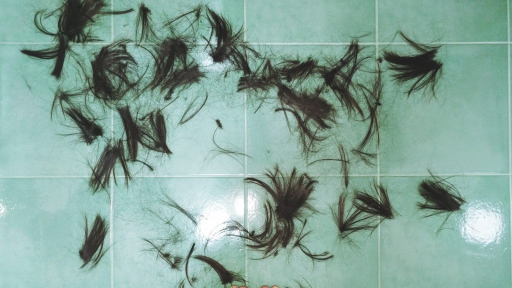 Brosse à cheveux posée sur un lavabo de salle de bains avec quelques cheveux tombés
