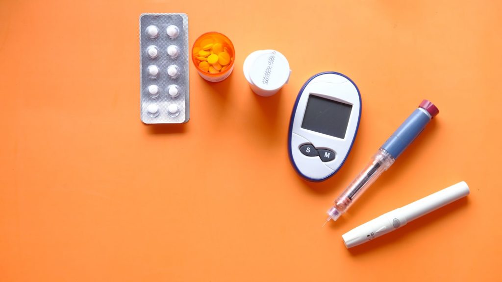 Lecteur de glycemie et comprimes poses sur une table, autosurveillance en diabete de type 2