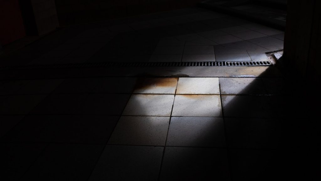 Pèse-personne posé au sol dans une salle de bains, sous la lumière naturelle du matin