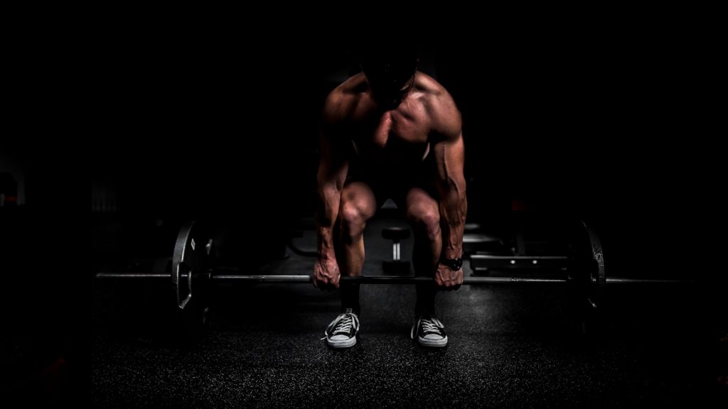 Pratiquant réalisant un squat à la barre dans une salle de musculation éclairée naturellement