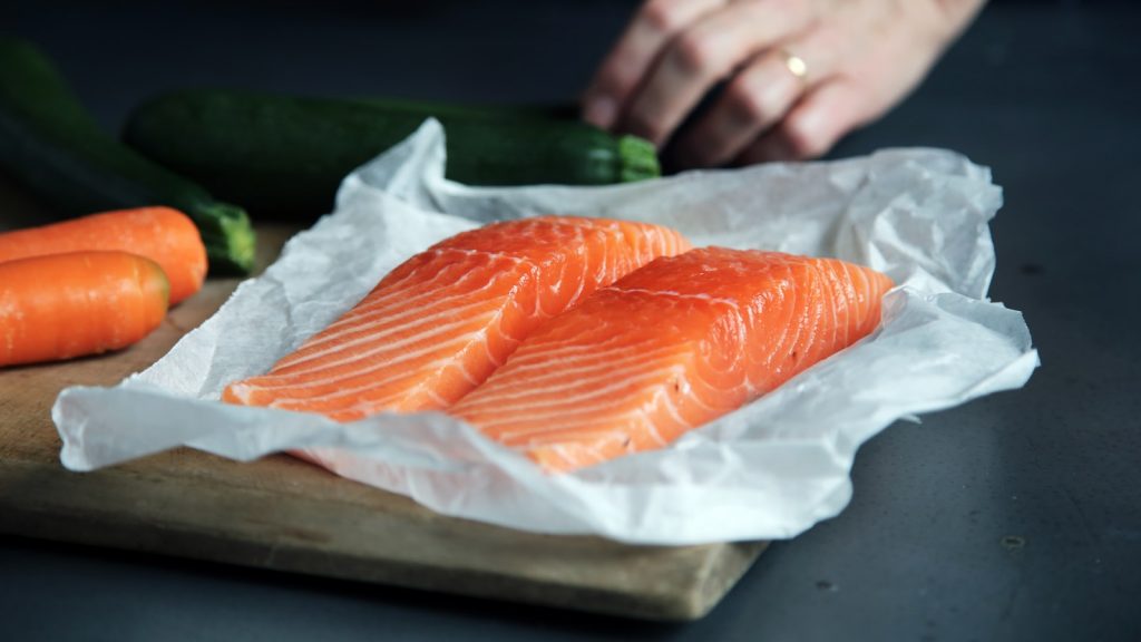 Pavé de saumon cru posé sur une planche en bois, lumière naturelle de cuisine