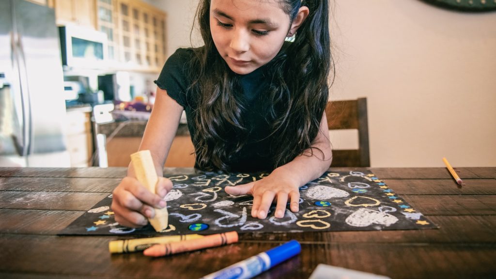 Enfant concentré sur ses devoirs à la table de la cuisine, illustration des troubles de l'attention